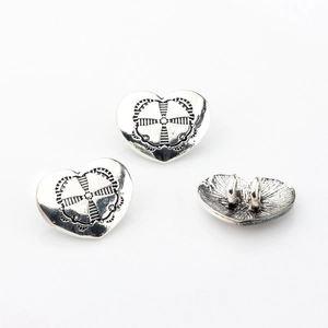 Macro shot of vintage heart-shaped alloy pendant charms with intricate floral engraving