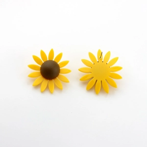 Détail macro de boucles d'oreilles tournesol jaunes montrant la texture mate et l'attache
