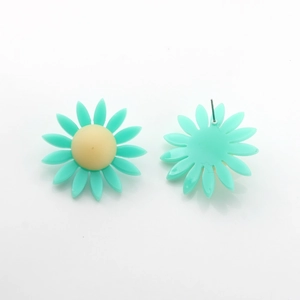 Vue macro de boucles d'oreilles marguerites avec pétales en résine bleue et coeur jaune