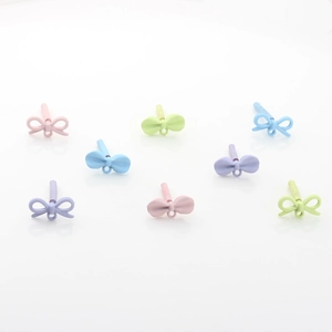 Matte alloy bow pendants in pastel colors for DIY jewelry making on white background