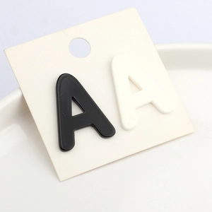 Minimalist black and white acrylic letter A stud earrings set on a white display card