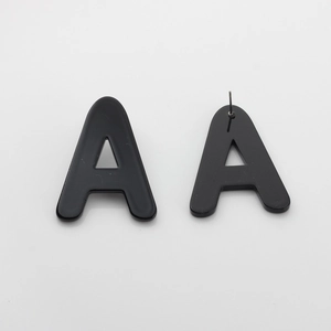 Macro shot of black acrylic letter A stud earrings with metal pins on a grey background