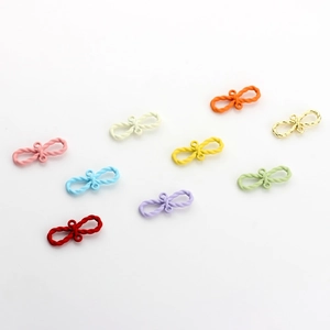 Gros plan de mini breloques nœuds colorés en alliage avec texture torsadée pour bijoux