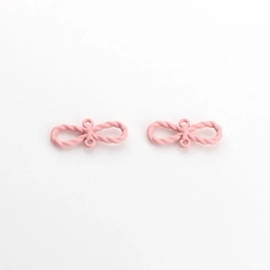 Détail macro de breloques nœuds roses mats avec texture torsadée pour création de bijoux
