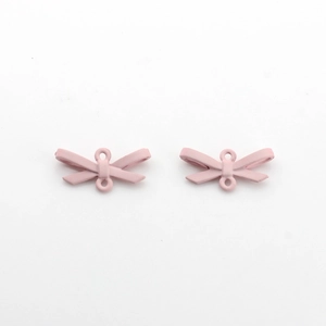 Gros plan de mini breloques nœuds roses en alliage mat pour création de bijoux et colliers