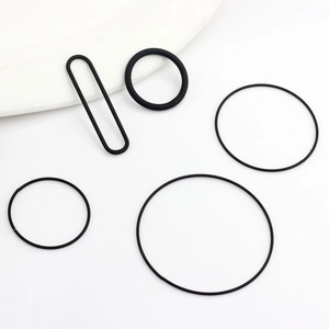 Detailed macro view of assorted black rubber O-rings and gasket seals on white background