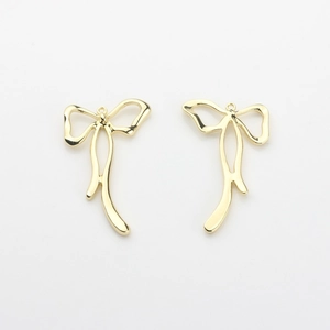 Close-up of golden bow-shaped metal pendants with polished mirror finish for DIY jewelry