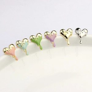 Lava heart enamel stud earrings in six colors hanging on a white ceramic bowl edge