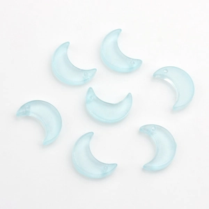 Détail macro de perles en verre translucide bleu clair en forme de lune avec petits trous percés