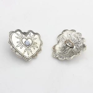 Macro shot of vintage silver heart-shaped button with lace texture and central bead detail