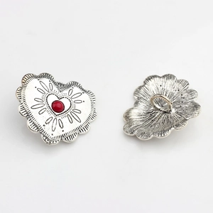 Macro view of vintage heart-shaped alloy buttons with red stone and embossed patterns