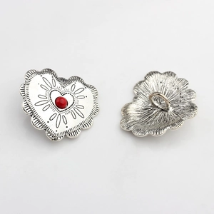 Detail of vintage heart-shaped alloy buttons with red center and antique silver lace edges
