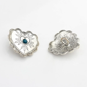 Detail of vintage heart concho with turquoise stone and scalloped antique silver edges