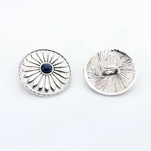 Detailed view of vintage silver sunflower button with blue gem and shank back structure