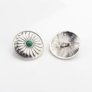 Detail of vintage silver sunflower alloy button with a green stone and back shank eyelet