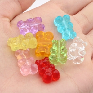 Macro view of colorful translucent resin bear charms held in hand for DIY size reference