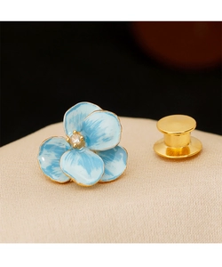 Macro detail of blue enamel flower brooch with crystal center and golden pin back