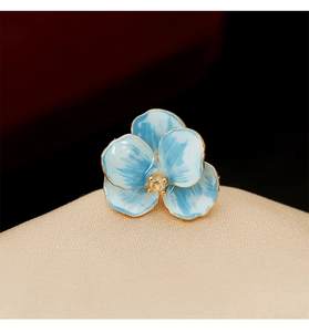 Macro detail of blue enamel iris brooch with golden edges and a sparkling center stone