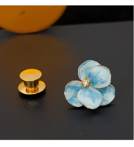 Macro view of blue enamel iris flower brooch with gold edges and zircon center