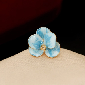 Elegant blue enamel iris flower brooch with gold plating and crystal center on display