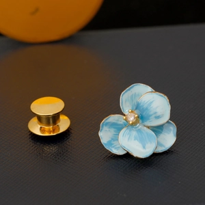Elegant blue enamel flower brooch with gold edges and central cubic zirconia stone