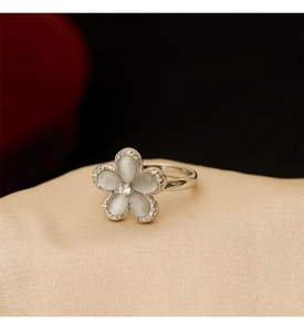 Macro shot of silver flower ring with white cat eye stone petals and zircon accents