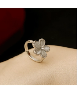 Macro detail of cat eye stone flower ring with zircon center on satin background
