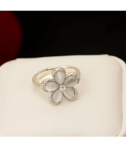 Detail of opal flower ring with sparkling zircon edges on a beige jewelry display stand