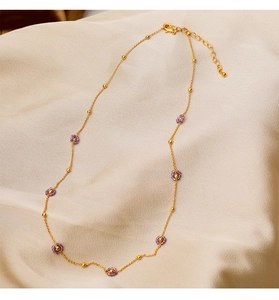 Detail of gold metal necklace with purple bead flowers and adjustable clasp closure