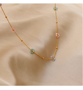 Detail of a gold-tone necklace with colorful bead flowers on beige silk fabric