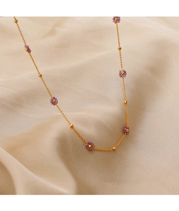 Detail of gold chain necklace featuring purple beaded flowers on silk fabric