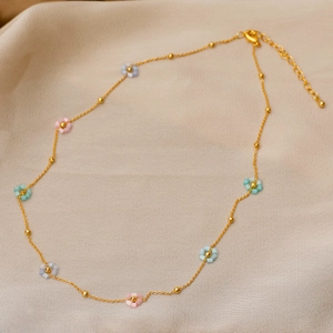 Golden necklace with colorful beaded flowers on premium silk fabric background