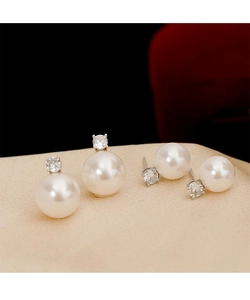 Gros plan de boucles d'oreilles perles et zircons ronds sur tissu en soie champagne