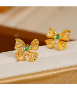 Vista macro de pendientes de mariposa con gema verde y detalles de metal dorado