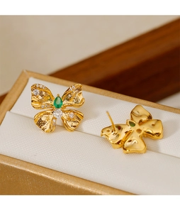 Detalle de pendientes de mariposa dorados con piedra verde gota y acentos de circón