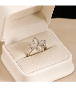 Macro shot of opal clover ring with pavé detailing in a beige velvet jewelry box
