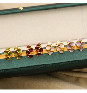 Close-up of wavy enamel clip-on earrings in multiple colors on a green jewelry box