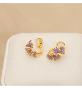 Macro shot of purple enamel flower clip-on earrings with gold wavy edges and silicone pads