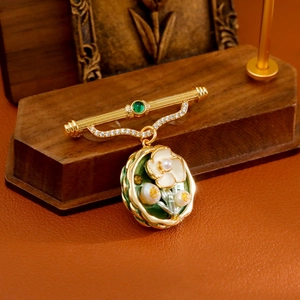 Broche vintage dorée avec fleurs en émail vert et perles sur un support en bois