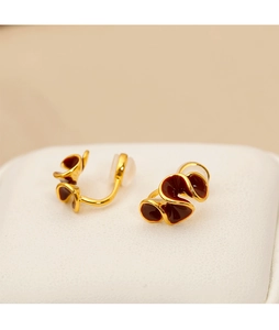 Detail view of gold wave-edged clip-on earrings with deep burgundy enamel and silicone pads
