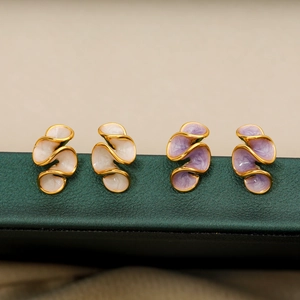 Elegant cream and lilac enamel floral spiral earrings on green leather jewelry box