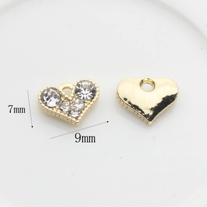 Vue macro de breloques en forme de cœur doré avec strass pour création de bijoux DIY