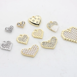 Sélection de pendentifs cœurs pour bijoux DIY avec perles et strass sur surface blanche