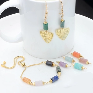 Detail of turquoise fan earrings and multi-color natural stone bracelet on white ceramic