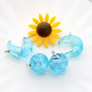 Cloud pattern blue resin moon and sphere pendants with silver metal clasps on white background
