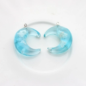 Detailed view of crescent moon resin pendants with blue sky and white cloud design