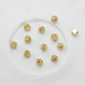Golden round bead-textured alloy charms for DIY jewelry making with 11 pieces on a white plate
