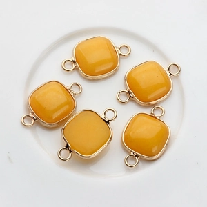 Macro detail of square yellow gemstone connectors with gold-plated metal frame for DIY jewelry