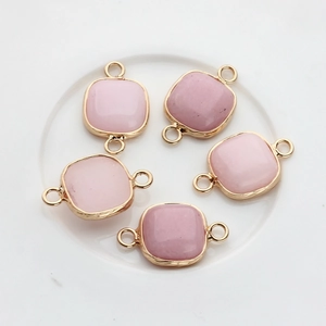 Detailed view of five square pink stone charms with gold-plated edges and double jump rings