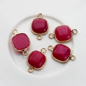 Macro view of square fuchsia stone pendants with gold-plated edges and double loops